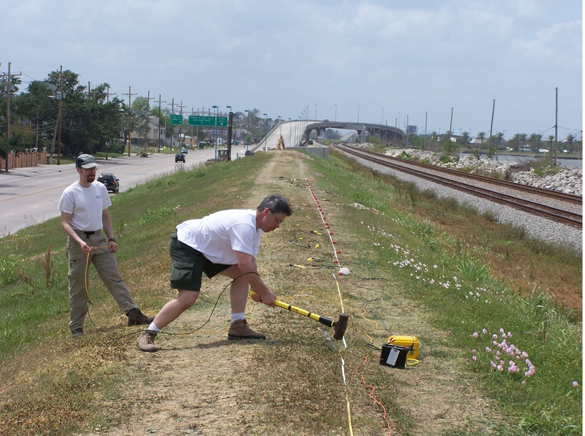 Figure 5. A USGS scientist hits a strike plate with a hammer to initiate a seismic wave in the subsurface. Travel times detected at the red geophones along the survey profile will be recorded by the seismograph (USGS 2006).